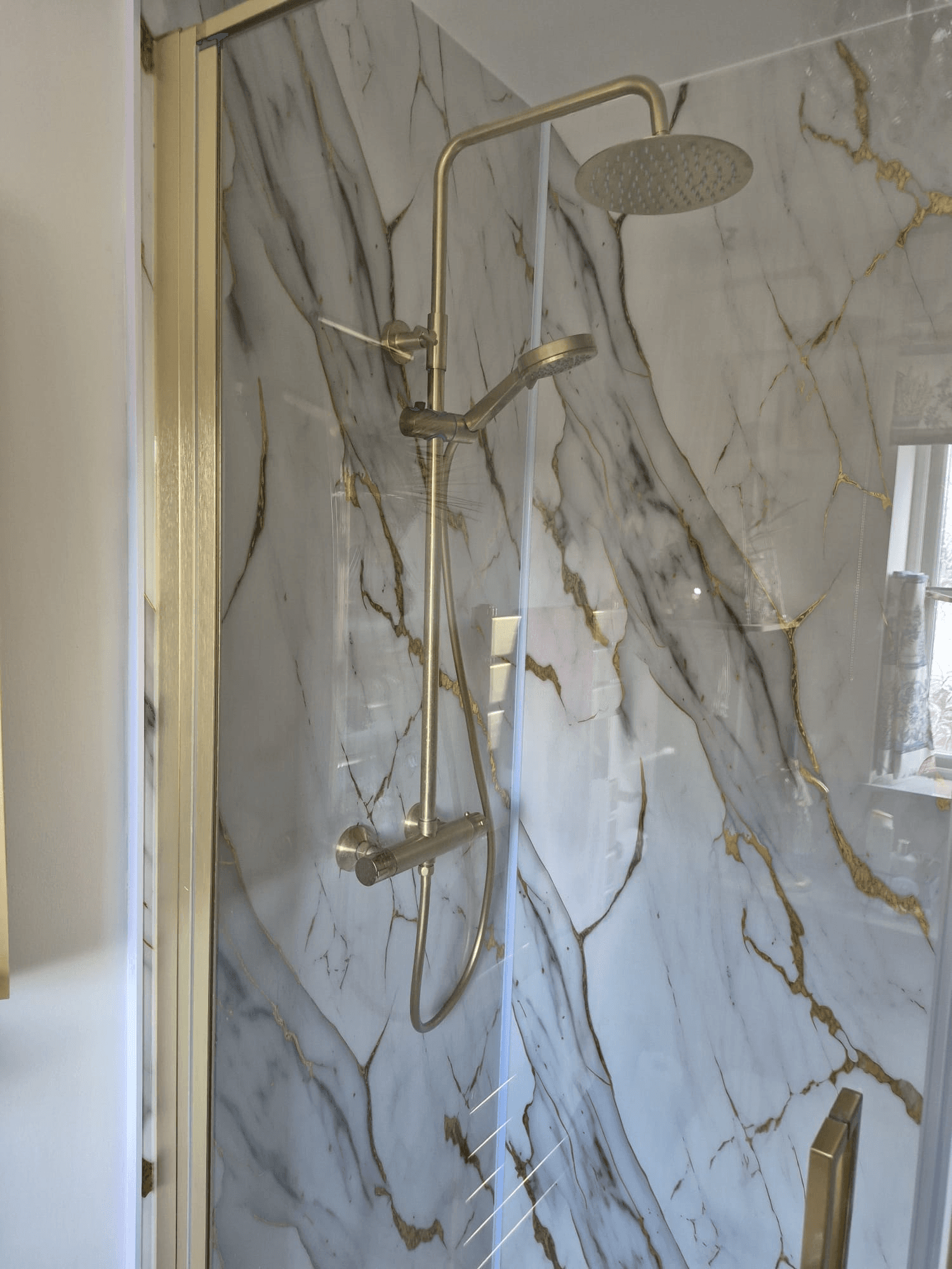 Marble-effect shower with gold fixtures